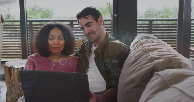 Vertical video: Leaning man guiding partner with laptop open on couch by window, explaining content