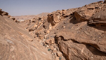 Vast barren landscape varying shades brown beige hues indicating desert-like environment terrain rocky uneven large jagged rocks b