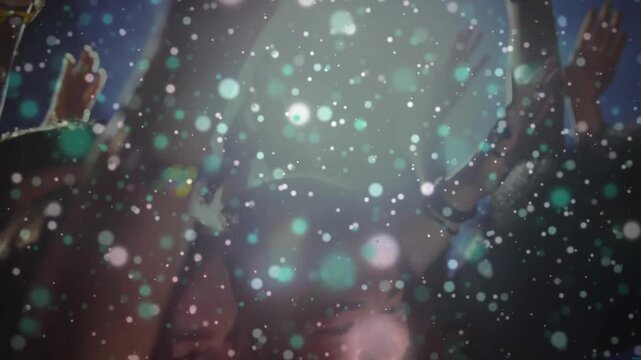 Concert crowd raising hands and reacting to stage performance while confetti drifting across cam