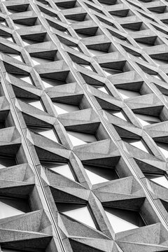Brutalist concrete facade geometry forms an abstract architectural pattern with deep shadow and textured structure for modern building design background