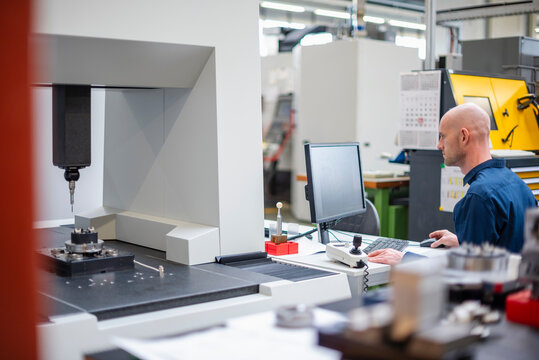 Engineer working at computer in industrial manufacturing facility