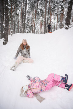 Mother and daughter playing joyfully in snow forest in winter