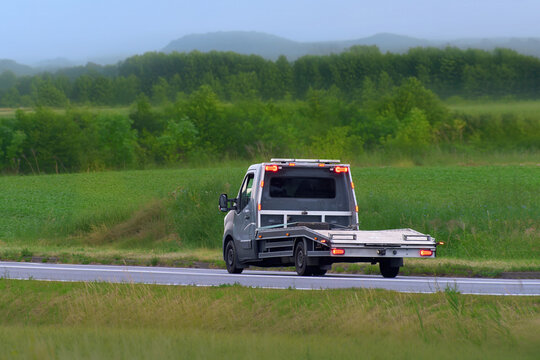 Empty flatbed tow truck driving on country road