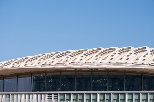 Modern architecture building facade exterior with windows in urban sky highlighting stadium roof design and structure with curved engineering detail