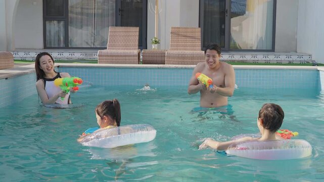 Happy family swimming and playing in the sparkling pool