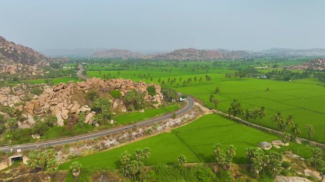 Beautiful aerial landscape of Tungabhadra River bridge with green fields and rocky hills in Hampi.
