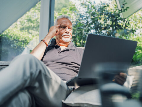 Angry man sitting on couch with laptop computer in living room