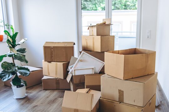 Stack of moving boxes with household items in empty room during relocation