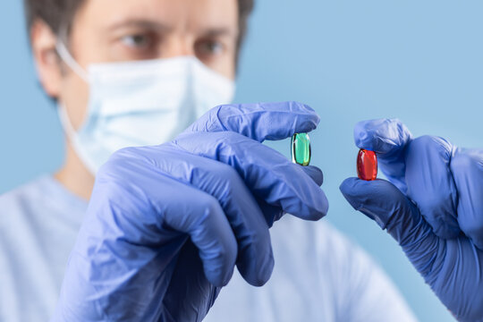 Doctor hands taking medicine capsule pills on blue background. a red and green pill in a doctor hand.