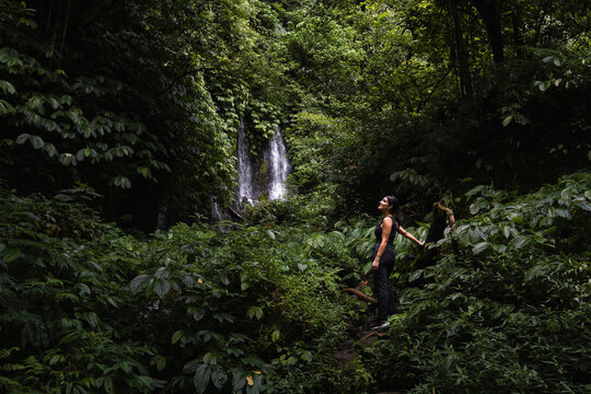 Woman exploring lush jungle near a waterfall in Bali Indonesia