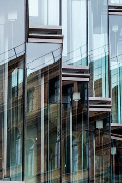 Modern architecture facade of layered glass windows with transparent lines and urban reflections creating a refined abstract background