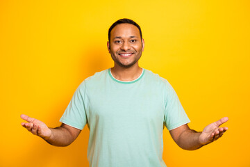 Smiling young man in casual mint shirt against bright yellow background for lifestyle fashion and...