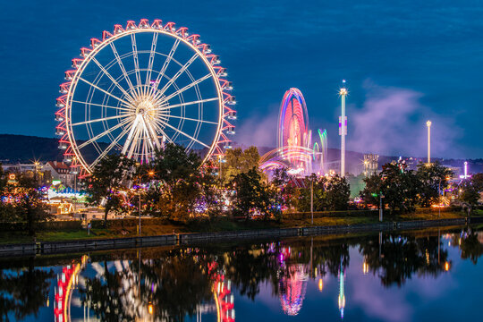 Ferris wheel and colorful rides at Cannstatter Volksfest in Stuttgart at night