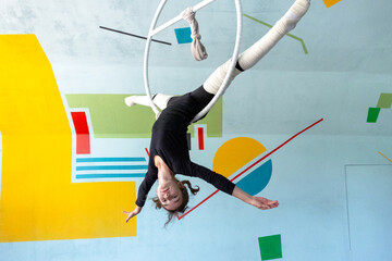 Flexible girl practicing aerial skills on hoop, child circus class, safe and elastic leg wraps, artistic acrobatic movement. © Ольга Симонова