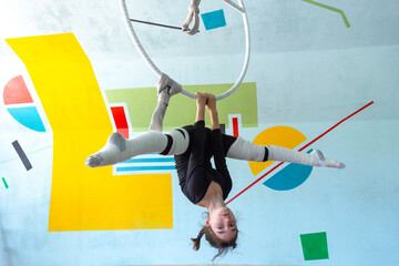 Young girl in black sportswear practicing aerial hoop movements, acrobatic technique, safety, elastic bandage for comfort. © Ольга Симонова