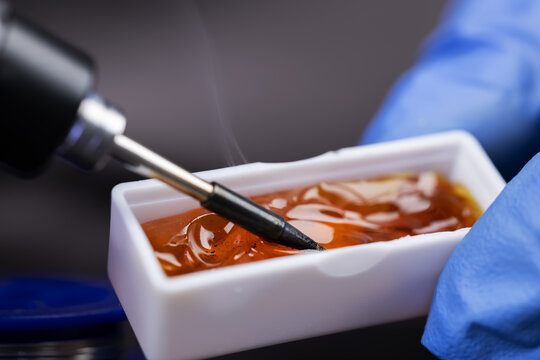 soldering iron tip and rosin on a black background. Tinning of the soldering iron tip with flux