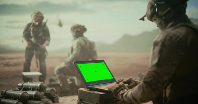 Soldiers Operating Green Screen Chroma Key Laptop for Enemy Tracking, Surveillance, Tactical Coordination as Helicopter Approaches Targets Middle East Desert Combat Zone. Battlefield Command Military