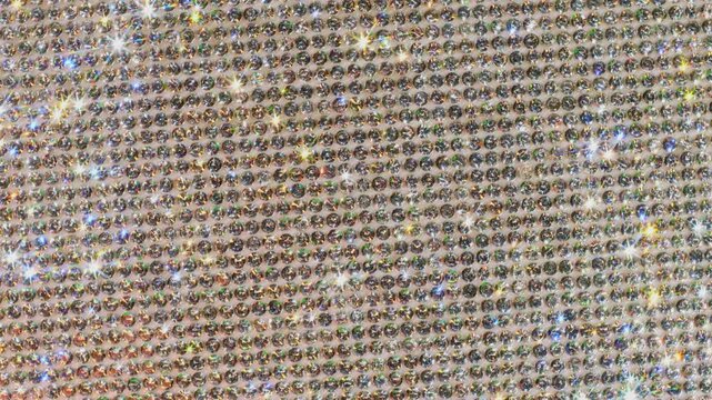 Seamless Rotating Silver Sparkling Crystals. Macro video of faceted rhinestones with intense bright star flares and smooth rotational camera movement on light surface in true seamless loop.