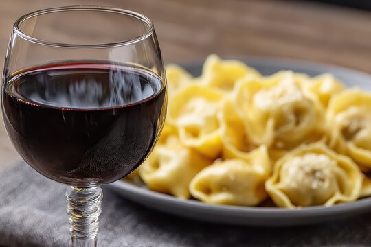Close up of a glass of red wine and plate of fresh cappelletti on a table, creating an elegant and delicious culinary scene perfect for gourmet dining.