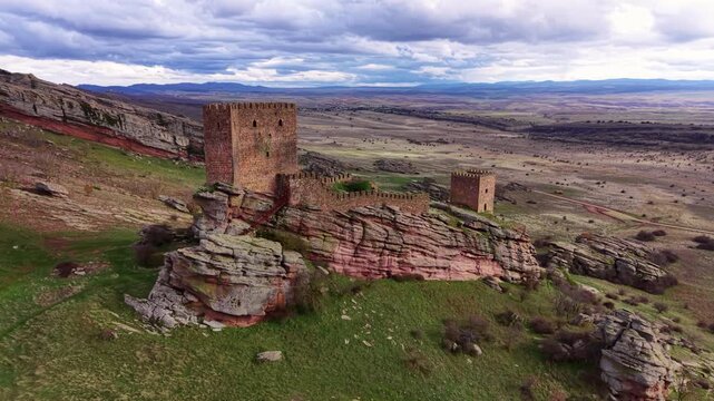 Aerial view of the ancient Castle of Zafra standing on a dramatic sandstone ridge in rural Spain, a medieval fortress known as a filming location featured in Game of Thrones