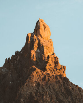 View of jagged peaks ablaze in the golden light of the setting sun against the tranquil sky, a majestic alpine vista, Trento, Trentino-Alto Adige, Italy.