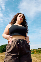 Young woman celebrates body positivity in a sunlit field surrounded by nature