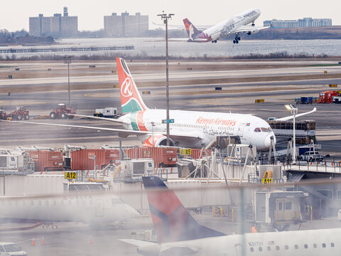 Kenya Airways Boeing 787 Dreamliner at gate as Hawaiian Airlines Boeing 787 takes off at JFK Airport, New York