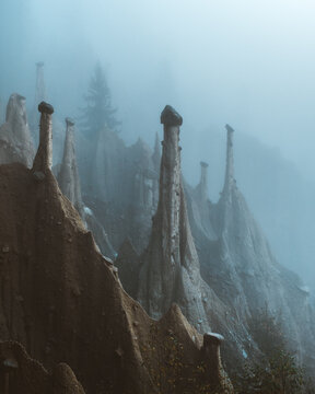 View of ethereal earth pyramids rise through the dense fog, their peaks barely visible in this mystical landscape, Renon, Trentino-Alto Adige, Italy.