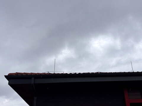 Lightning rods on a modern building roof against cloudy grey sky