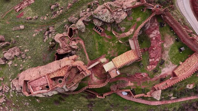 Top-down aerial view of the ancient Castle of Peracense in Aragon, Spain, showing fortified sandstone walls, internal courtyards and medieval siege machines inside the historic mountain fortress
