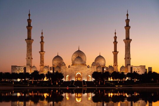 View of the majestic Sheikh Zayed Mosque reflecting in the still waters at sunset, Abu Dhabi, United Arab Emirates.