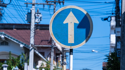 Weathered blue circular mandatory direction sign with upward arrow on a Thai urban street © WD Stock Photos