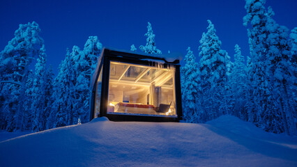 Snowy glass cabin illuminating the winter landscape in Akaslompolo, Lapland, Finland