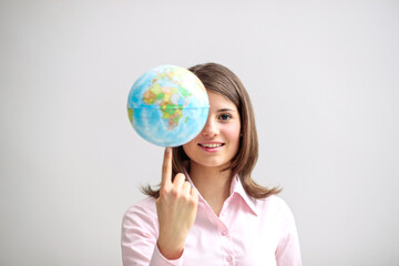 Fototapeta premium Eine junge Frau balanciert kleinen Globus auf dem Finger, Symbol für Globalisierung, internationale Verantwortung und weltweite Vernetzung, KI-Generiert
