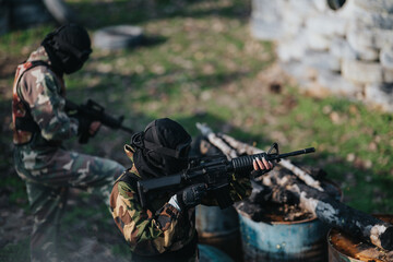 Fototapeta premium Paintball players in tactical gear practice shooting outdoors, focusing on teamwork and safety.