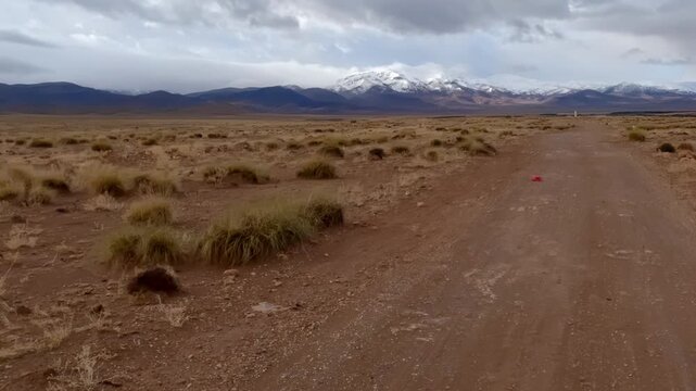 First person perspective driving on a moroccan desert road towards snowy mountains