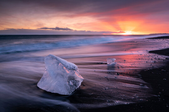 Diamond Beach at sunset, block of ice on a strip of black sand belonging to the greater Breioamerkursandur glacial plain, Jokulsarlon glacier lagoon, south coast of Iceland. February, 2024. 