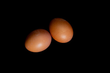 Obraz premium Two boiled eggs in orange shells on a black background,
