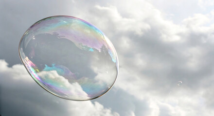 Naklejka premium A mesmerizing iridescent soap bubble floats gracefully across a dynamic cloudy sky, reflecting vibrant hues
