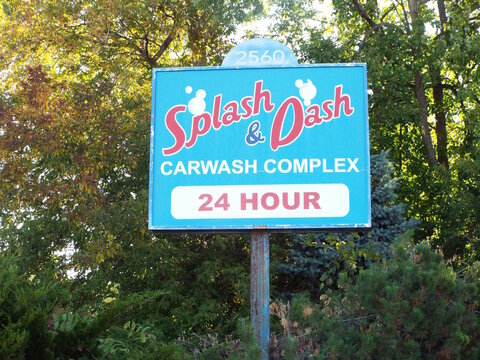 Ottawa, Ontario, Canada-July 19, 2025: A blue roadside sign for "Splash & Dash Carwash Complex" at 2560 Bank Street indicates 24-hour service availability .