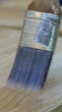 Protective enamel covers wooden surface as brush moves precisely, ensuring even application. Glossy layer seals fibers, reinforcing durability. Light accentuates smooth, polished result