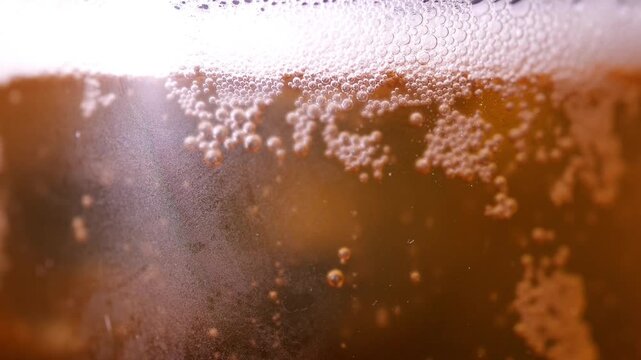 Close-up of cold draft beer being poured into glass with frothy foam head