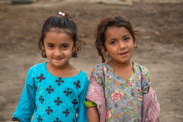 Two Smiling Young Girls Standing Together in a Rural Village Setting