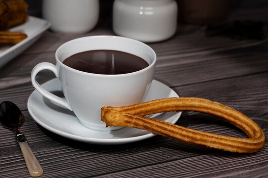Churros pastry with hot chocolate drink on wooden table