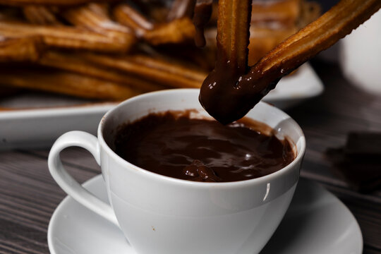 Homemade churros with hot chocolate on dark background