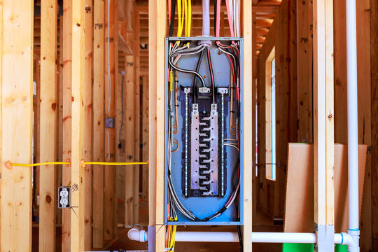 Electrical panel installation in new home under construction with exposed framing wiring hallway