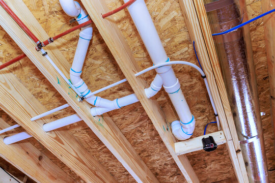 Pipes ducts installed under wooden ceiling in construction site for building project