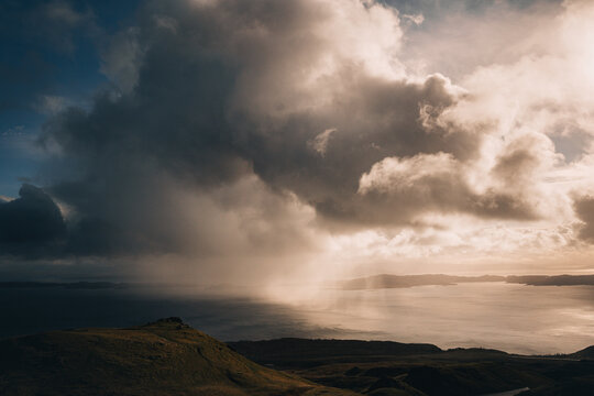 View of dramatic clouds casting shadows over the rugged terrain and the shimmering sea, Isle of Skye, Scotland, United Kingdom.