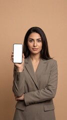 Naklejka premium Young woman in business suit holding smartphone forward confidently indoors