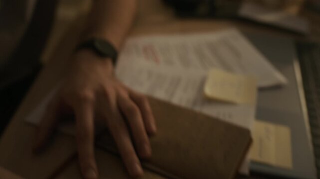 Handheld shot of sad gen Z man holding photograph of ex-girlfriend and trying to forget about past while sitting at table with notebook and glass of drink